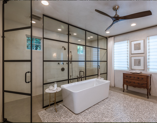 Designer in-lay tile work with luxurious custom iron and glass shower in master bathroom with 50 gallon freestanding tub in Houston, TX.